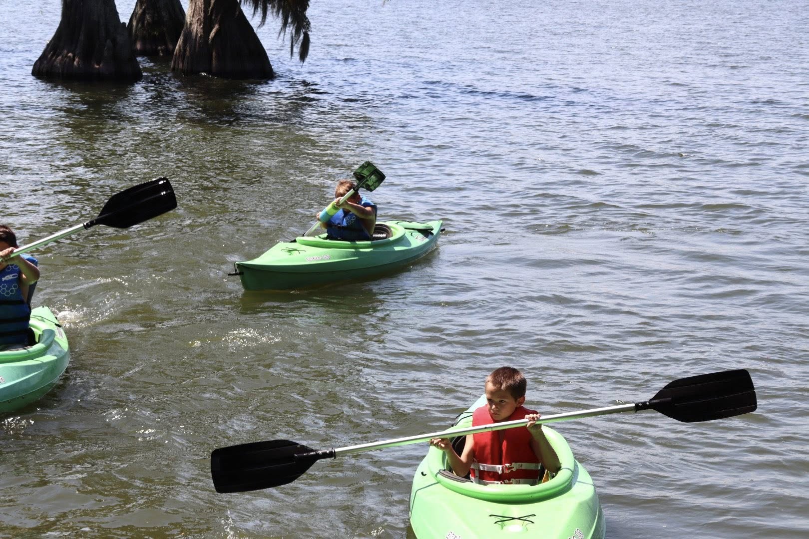 Three people kayaking in a lake.